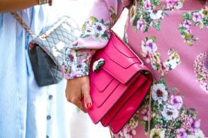 women holding pink and blue designer handbags bvlgari and chanel